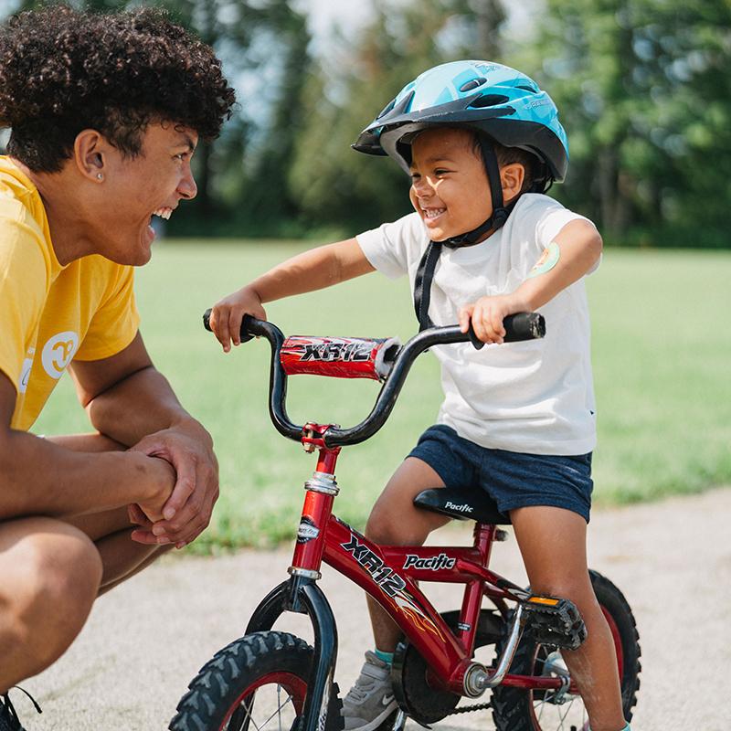 young boy on bike with instructor at bike camp